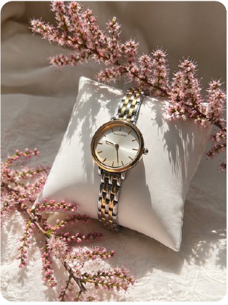 Photo produit d'une montre posée sur un coussin, avec des fleurs roses